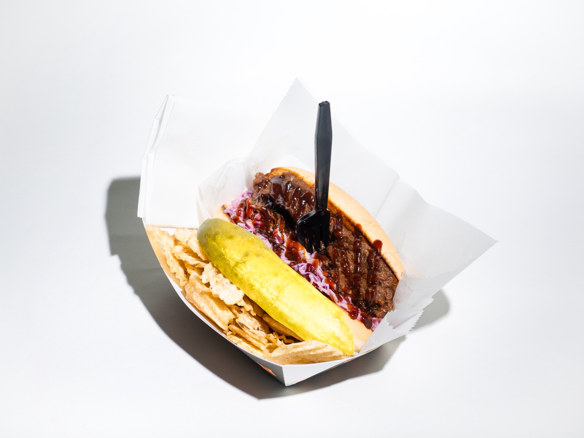 15-to-Life BBQ Brisket Sandwich with slaw, pickle spear, and kettle chips